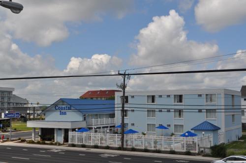 a white building with a blue roof next to a road at Coastal Inn - Ocean City in Ocean City