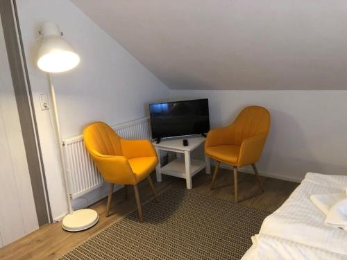 a room with two chairs and a tv and a bed at ZUM BAHNHÖFLE Restaurant & Hotel - Albbruck Am Rhein in Albbruck