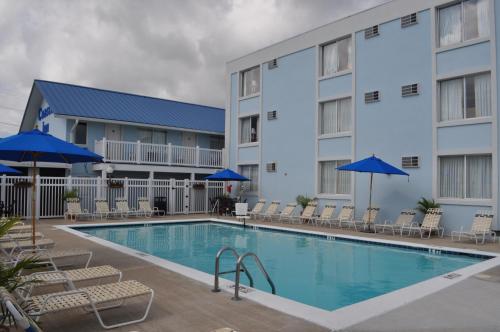a pool in front of a hotel with chairs and umbrellas at Coastal Inn - Ocean City in Ocean City