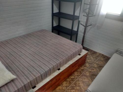 1 dormitorio con 2 camas y estante para libros en Chalés Ki Bakana, en Ubatuba