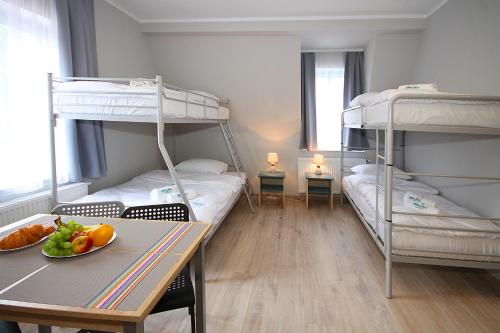 a room with two bunk beds and a table with a bowl of fruit at Willa Park Apartamenty in Olsztyn