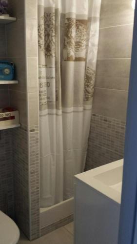 La salle de bains est pourvue d'une douche avec rideau de douche blanc. dans l'établissement Studio avec jardinet clim parking, à Gruissan