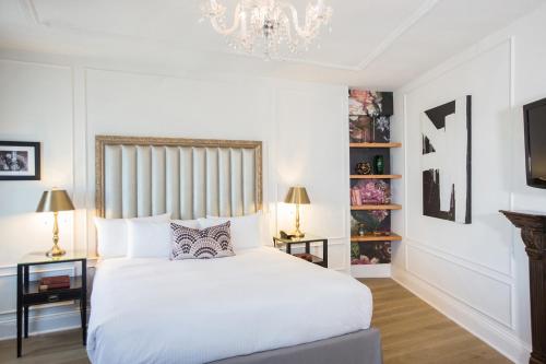 a bedroom with a white bed and a chandelier at The Culver Hotel in Los Angeles