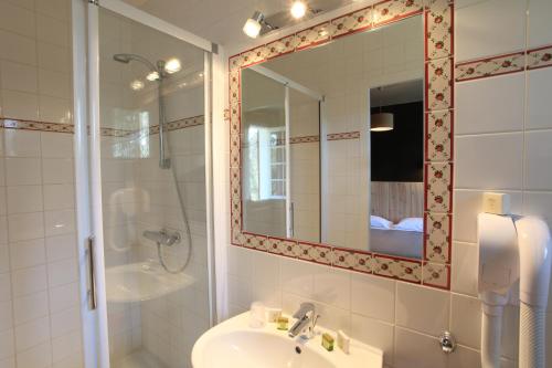 uma casa de banho com um lavatório, um chuveiro e um espelho. em Hôtel La Paloma em Hossegor