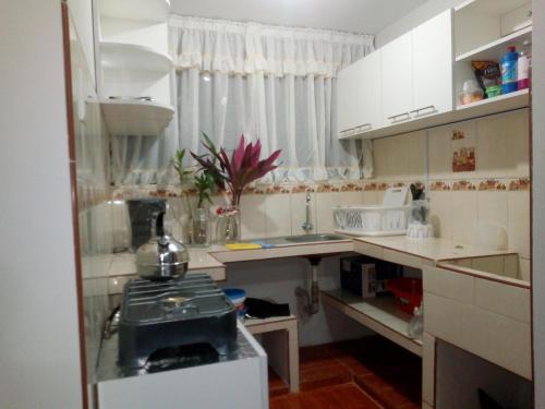 una pequeña cocina con armarios blancos y fregadero en Sumak Samana Wasi, en Lima