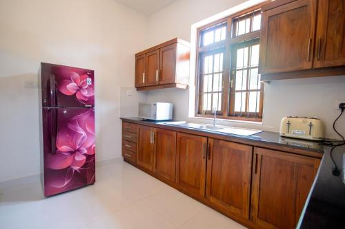 a kitchen with wooden cabinets and a refrigerator at NegomboVilla in Negombo