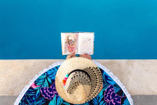 una persona con un sombrero de paja leyendo un libro en Soho Playa Hotel, en Playa del Carmen