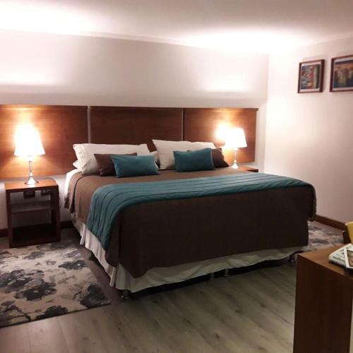 a bedroom with a large bed with two lamps at Hotel D&V Concepción in Concepción