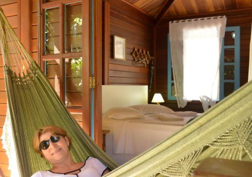 a woman sitting in a hammock in a bedroom at Pousada Encontro dos Rios in Lumiar