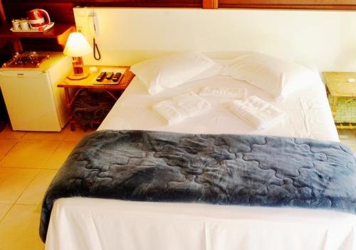 a bedroom with a bed with white sheets and pillows at Pousada Encontro dos Rios in Lumiar