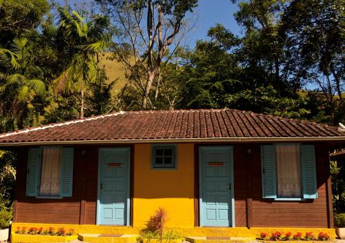 a small house with blue shutters and a roof at Pousada Encontro dos Rios in Lumiar
