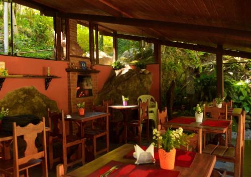 a restaurant with tables and chairs and a fireplace at Pousada Encontro dos Rios in Lumiar