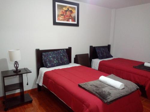 Habitación con 2 camas y mesa con lámpara. en Sumak Samana Wasi, en Lima