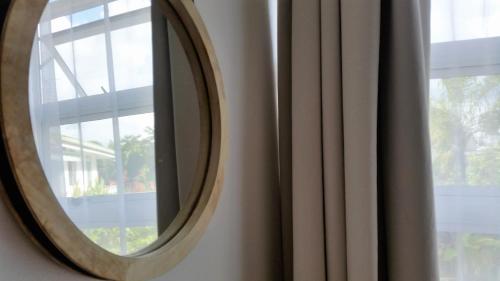 a round mirror on a wall next to a window at Fare Suisse Tahiti - Guesthouse in Papeete