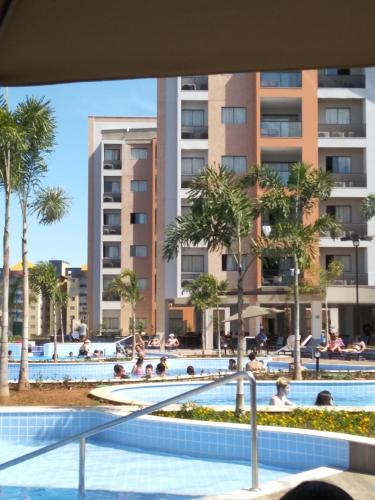 una piscina en un complejo con palmeras y edificios en Alta Vista Thermas Resort, en Caldas Novas