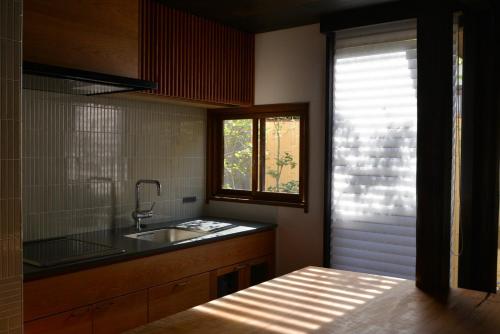 une cuisine avec un évier et une fenêtre dans l'établissement 滔々 御崎 町家の宿 toutou Onzaki Machiya no Yado, à Kurashiki