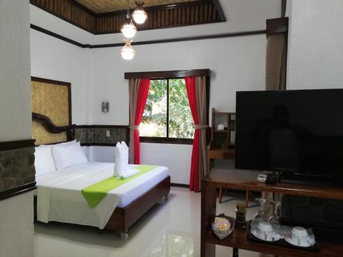 a bedroom with a bed and a flat screen tv at El Nido Viewdeck Cottages in El Nido