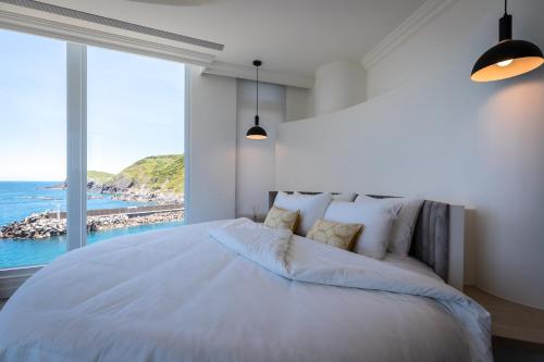 a bedroom with a large bed with a view of the ocean at Brighthouse in Suao