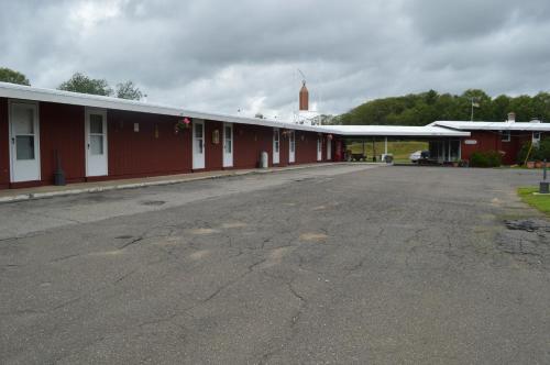 an empty parking lot next to a red building at Copper Lantern Motor Lodge in West Brookfield