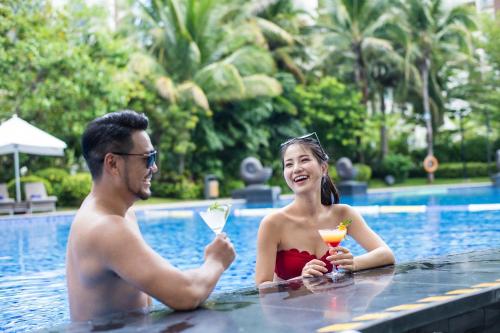 a man and woman in a swimming pool with drinks at Ramada Plaza by Wyndham Sanya Bay in Sanya