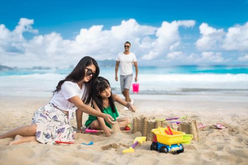 a woman and a girl playing in the sand on the beach at Ramada Plaza by Wyndham Sanya Bay in Sanya