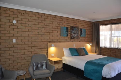 a hotel room with a bed and a chair at Sunray Motor Inn in Toowoomba