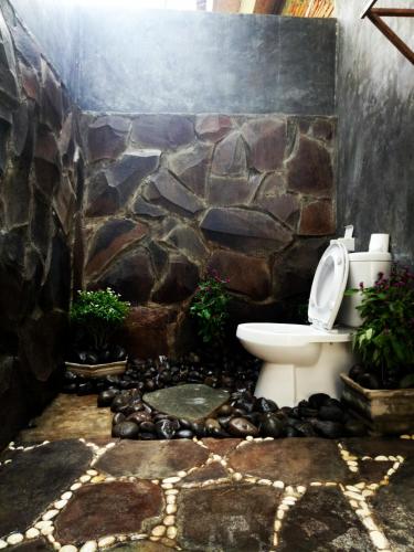 a bathroom with a toilet and a stone wall at Mengalung Bungalow in Kuta Lombok