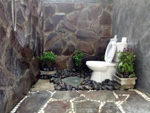 a bathroom with a toilet in a stone wall at Mengalung Bungalow in Kuta Lombok