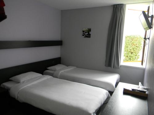 two beds in a hotel room with a window at Class-Hôtel in Poitiers