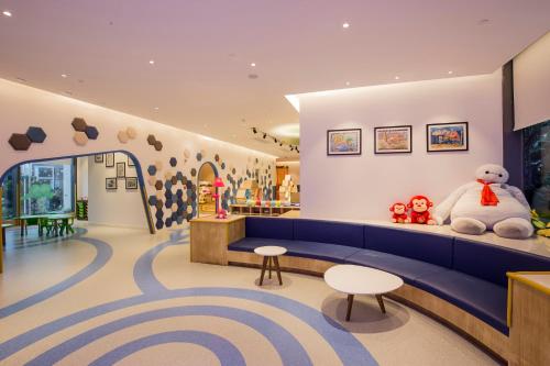 a waiting room with a blue couch and a teddy bear at Ramada Plaza by Wyndham Sanya Bay in Sanya