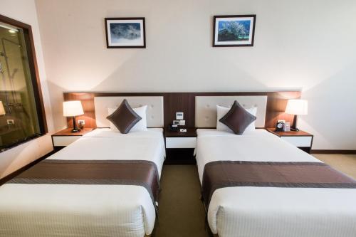 two beds in a hotel room with two lamps at Muong Thanh Grand Hoang Mai - Nghe An in Hoang Mai