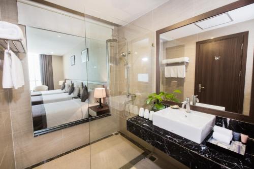 a bathroom with a sink and a large mirror at Muong Thanh Grand Hoang Mai - Nghe An in Hoang Mai
