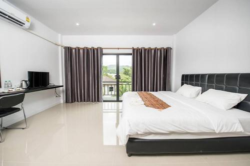 a bedroom with a bed and a desk and a window at Mr.T Kamala Room in Kamala Beach