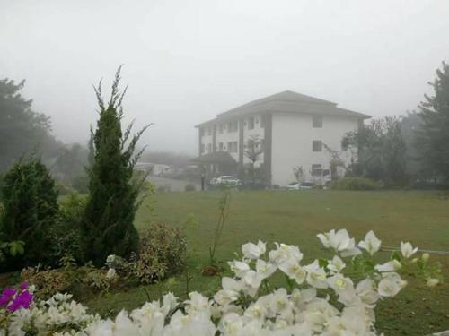 a large white house in a field with flowers at Ing Loei Place in Loei