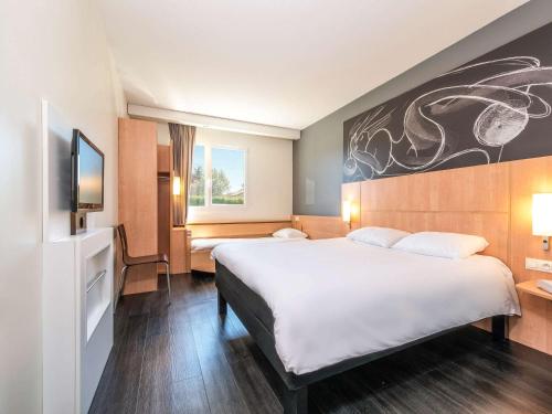 a hotel room with a large bed and a tv at ibis Issoire in Issoire