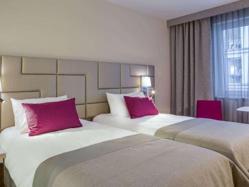 two beds in a hotel room with red pillows at Mercure Krakow Stare Miasto in Kraków