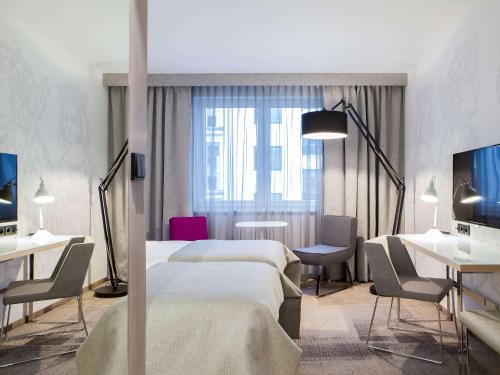 a hotel room with two beds and a desk at Mercure Krakow Stare Miasto in Kraków