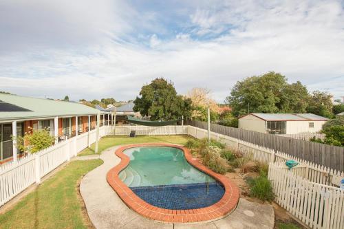 a backyard with a swimming pool and a fence at Rose Garden Motel in Geelong