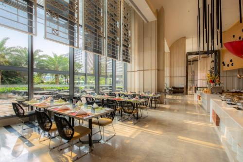 a dining room with tables and chairs and large windows at Wyndham Sanya Bay in Sanya