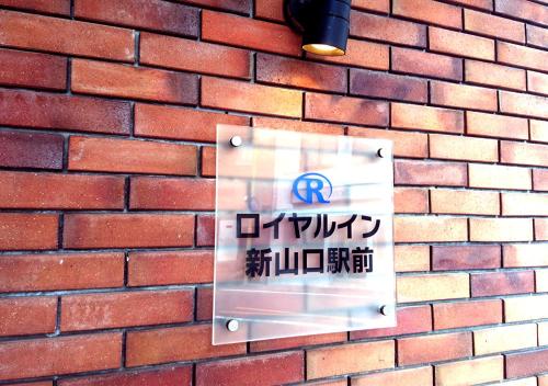 una señal en el costado de una pared de ladrillo en Royal Inn Shinyamaguchi Ekimae, en Yamaguchi