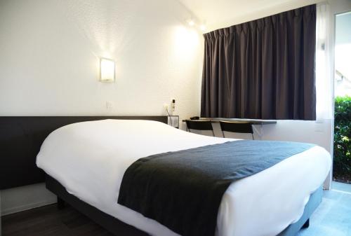 a hotel room with a large bed and a table at Aerel Hotel Aéroport Blagnac in Blagnac