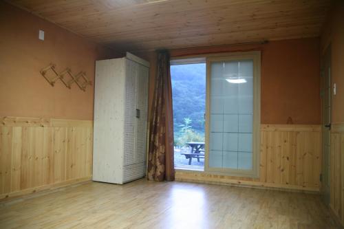 pusty pokój z dużym oknem i drzwiami w obiekcie Byelgang Pension w mieście Jeongseon