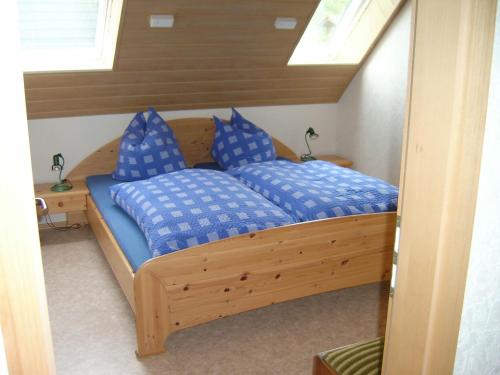 a bedroom with a wooden bed with blue pillows at Moselblick in Sankt Aldegund