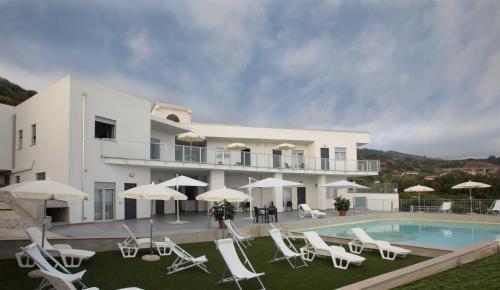 a large white house with a swimming pool and chairs at Cala Del Faro Beach Villas in Cittadella del Capo