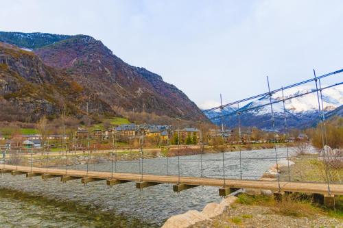a bridge over a river with a mountain at Ca' la Júlia Vall de Boi in Barruera