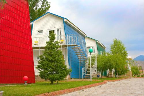 a blue and white barn with a tree in front of it at Отель Мармелад Иссык-куль in Bosteri