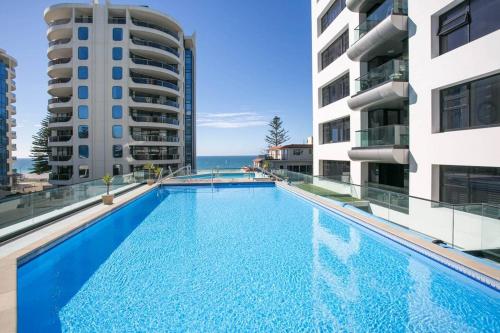 a swimming pool in the middle of two buildings at Luxury Ocean & Harbour Views - Heated Pool, Main Beach & Gym in Mount Maunganui