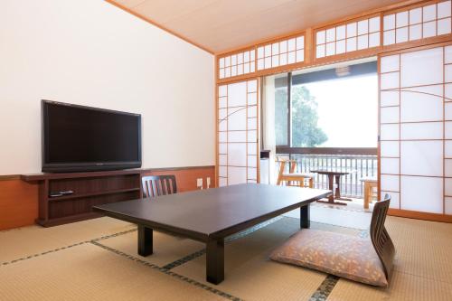 a living room with a table and a flat screen tv at Kikunoya in Miyajima