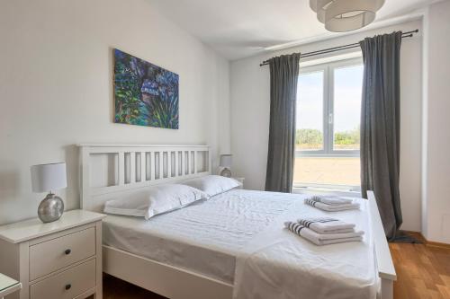 a white bedroom with a bed and a window at Apartment Genco in Peroj