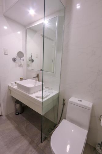 a white bathroom with a toilet and a sink at Hotel Carlito Tagaytay in Tagaytay